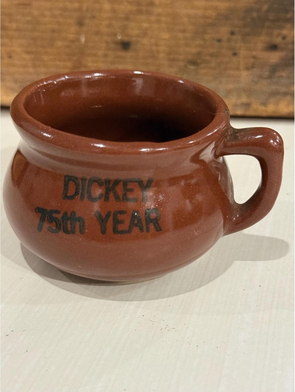 This is a commemorative "Dickey 75th Year" advertising stoneware mug.